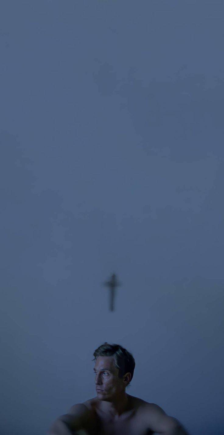 a man sitting in front of a cross at night