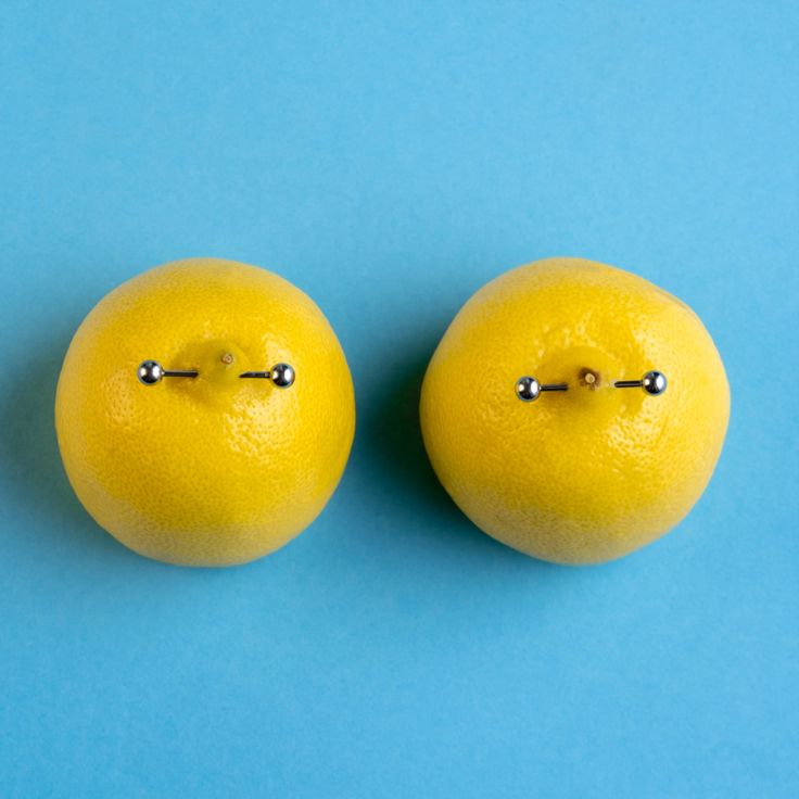 two lemons with metal pins on them sitting side by side against a blue background