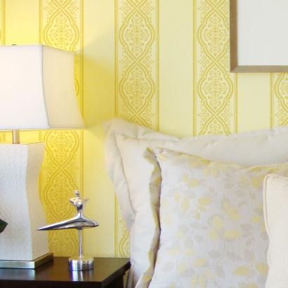 a bedroom with yellow wallpaper and white pillows