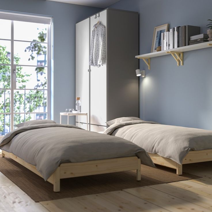 two beds in a room with blue walls and wooden floors, one is made up