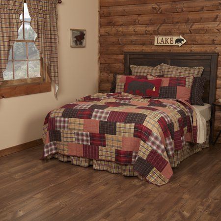 a bed in a room with wooden walls and wood flooring, along with two windows