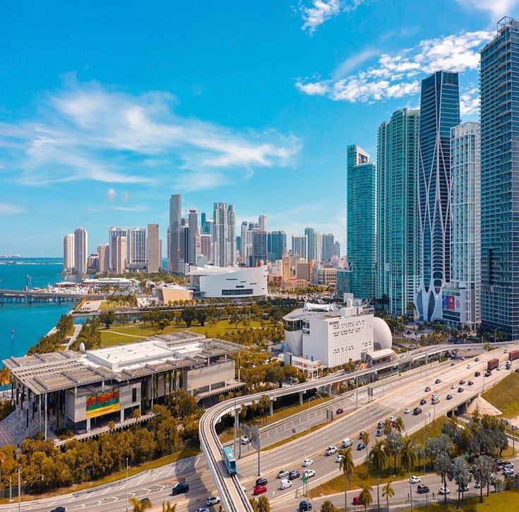 an aerial view of a city with tall buildings and cars driving on the road in front of it