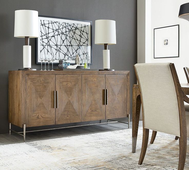 a dining room table with two lamps on it and a sideboard in the middle