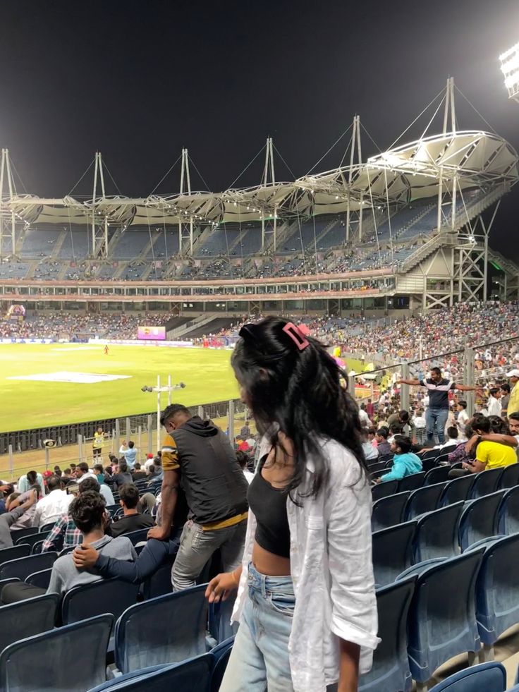 a woman standing in the stands at a baseball game