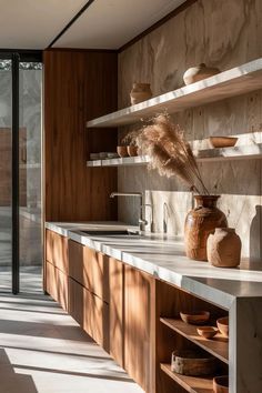 a kitchen with wooden cabinets and shelves filled with vases on top of it's counter tops