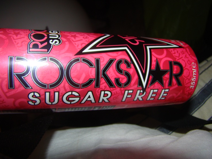 a can of rock star sugar - free soda sitting on a bed in the dark