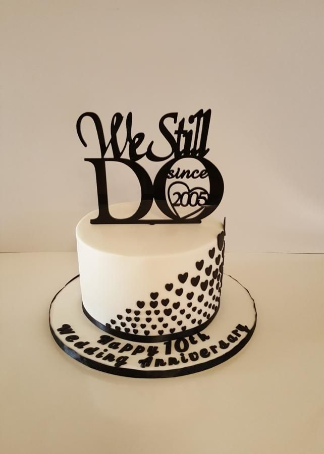 a white cake with black lettering and hearts on the top that says we still do