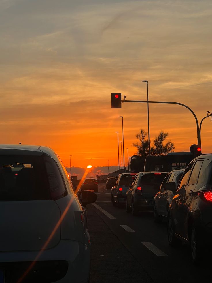 the sun is setting behind some cars in traffic