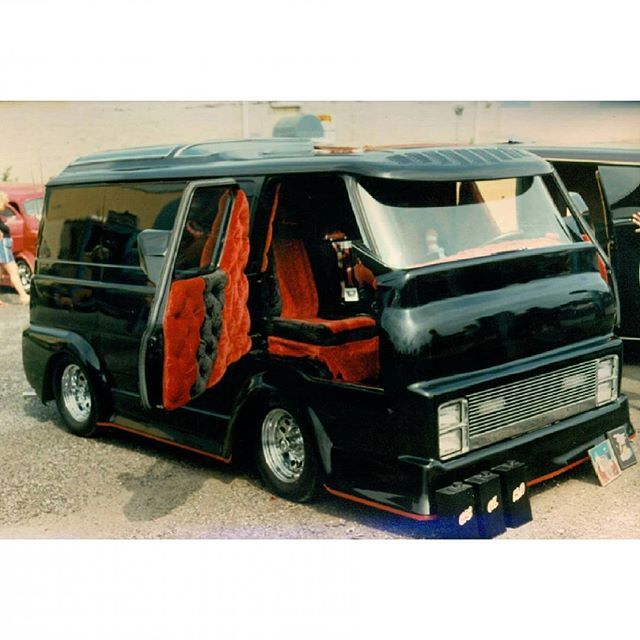 a black van parked in front of a building with red curtains on it's side