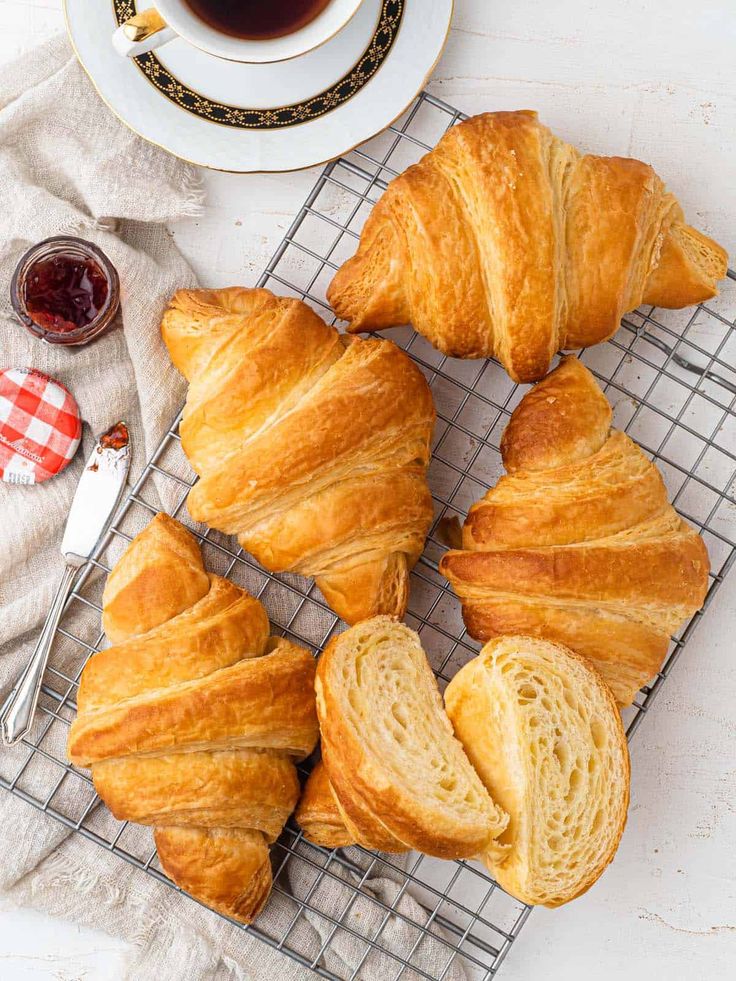 several croissants on a cooling rack next to a cup of coffee