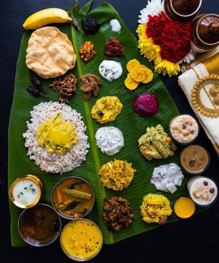 food is laid out on a banana leaf with other foods in bowls and sauces