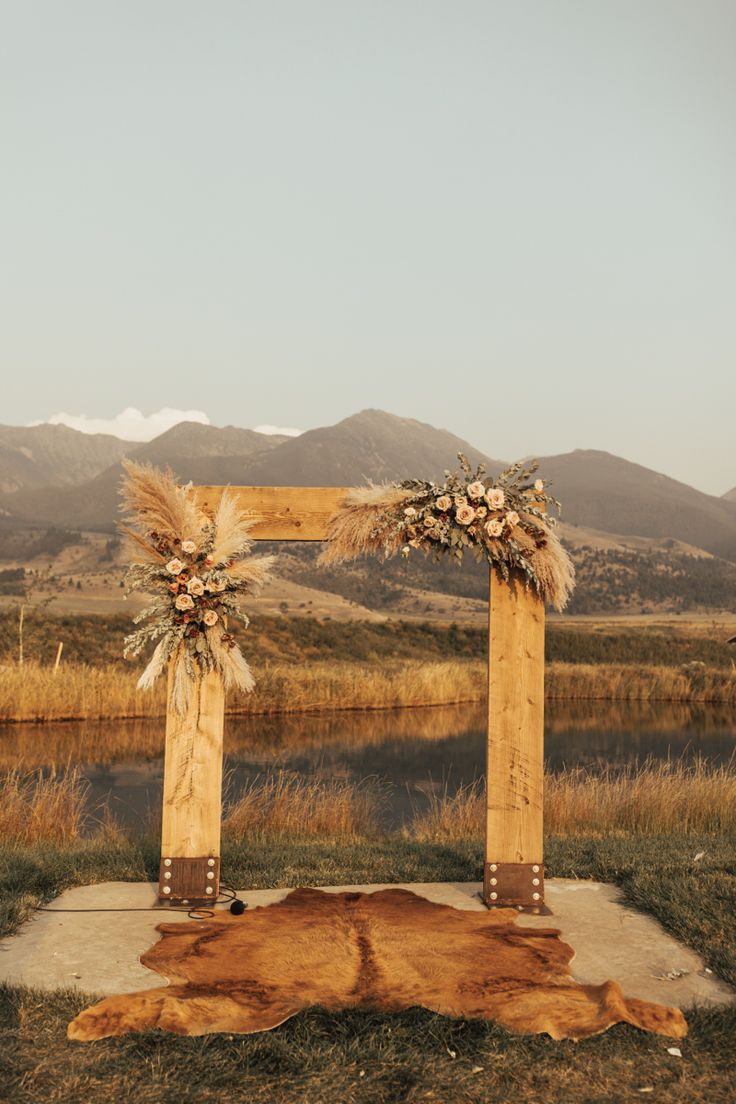 an outdoor ceremony setup with flowers and greenery on the ground in front of mountains