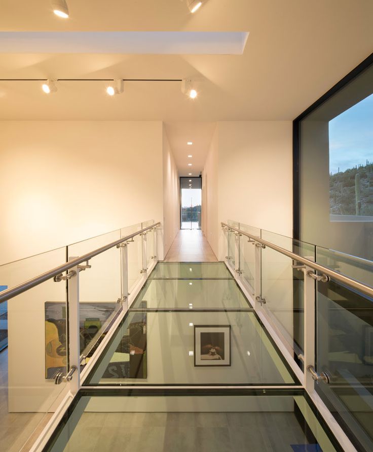 an empty hallway with glass railings leading up to the second floor