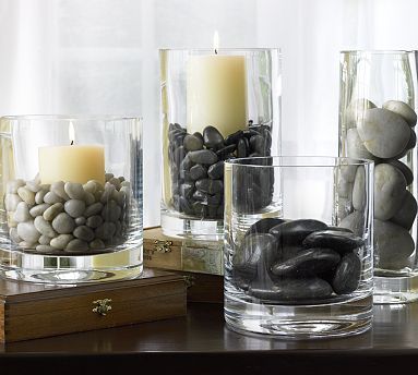 three glass vases filled with rocks and candles