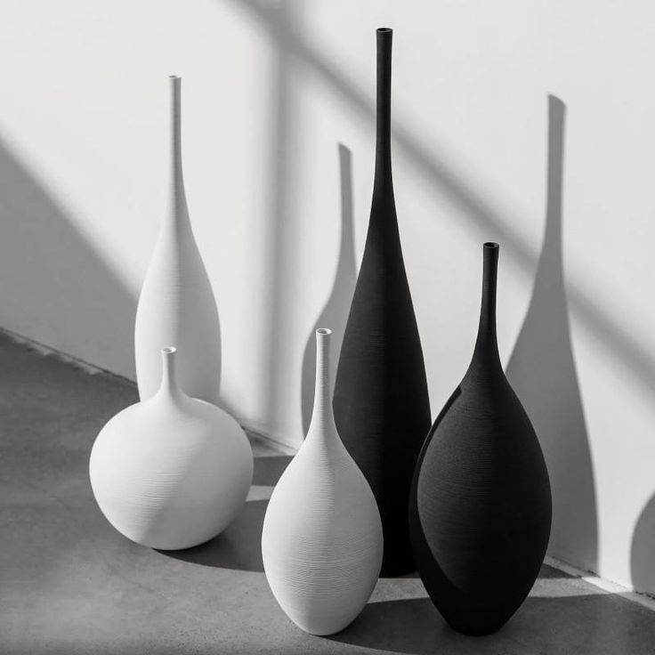 four black and white vases sitting on a table