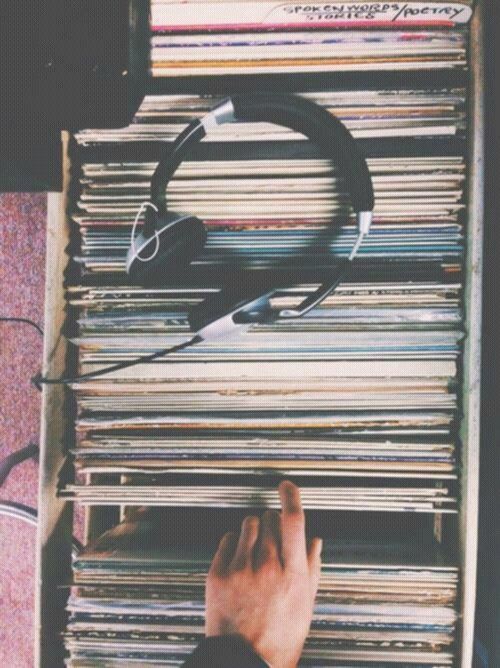 a person is looking at an old record player's headphones on top of a stack of records