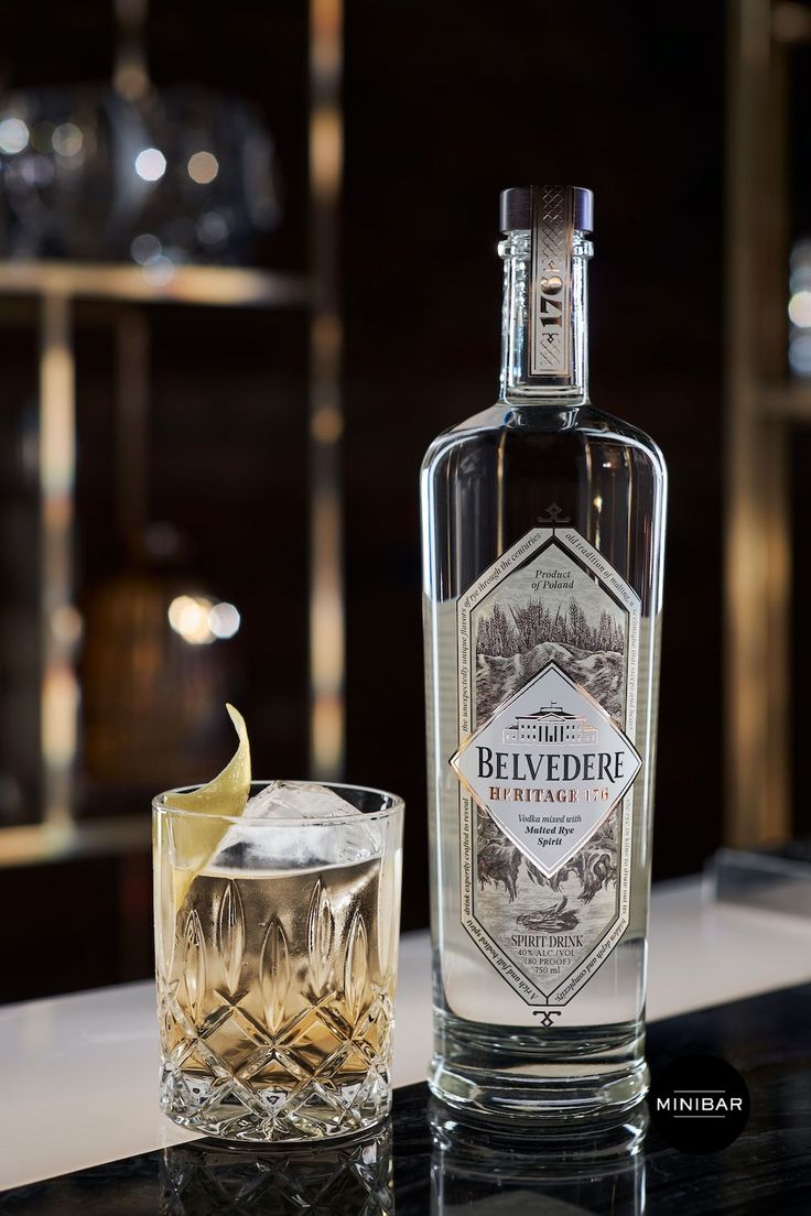 a bottle of belveder vodka next to a glass with a slice of lemon on it