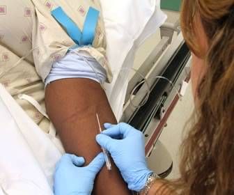 a woman is in the hospital with her arm wrapped around someone's hand and wearing blue gloves