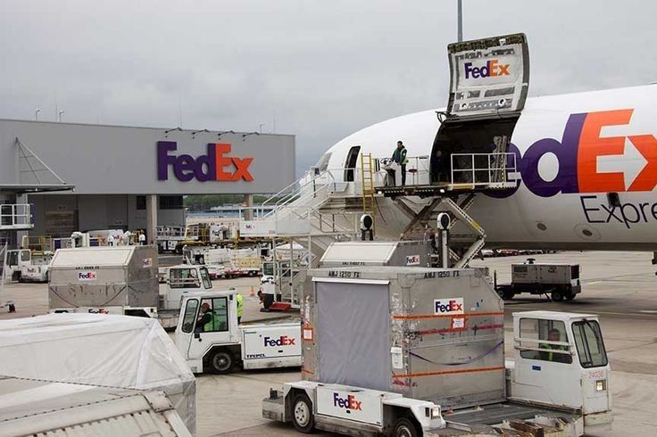 the fedex airplane is parked on the tarmac with other vehicles around it and people boarding