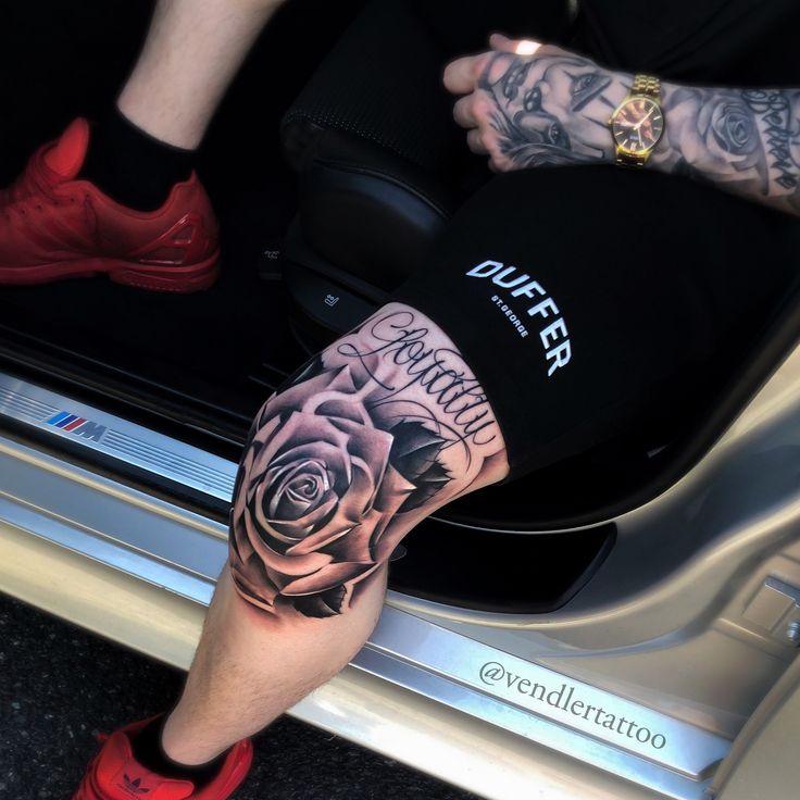 a man's leg with tattoos and roses on it, sitting in the back of a car