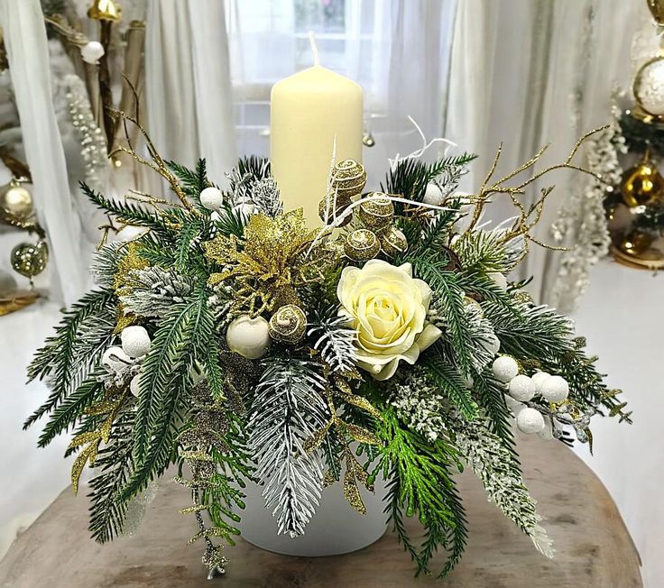 a candle is lit on top of a table with greenery and flowers in it