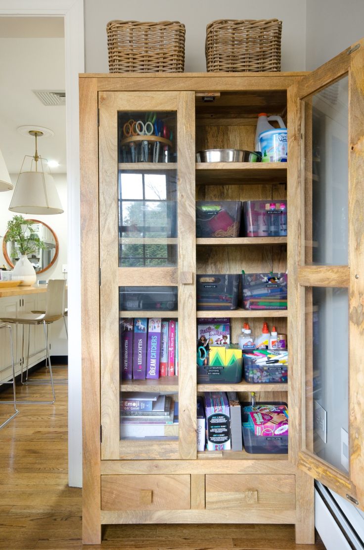 a wooden bookcase with glass doors and baskets on top