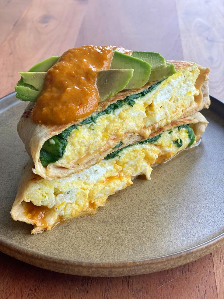 an omelet is cut in half on a plate with sauce and avocado