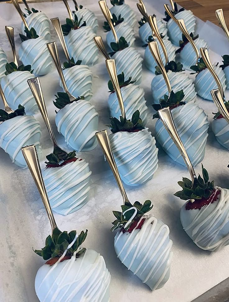 chocolate covered strawberries are lined up on a white tray with gold forks sticking out of them