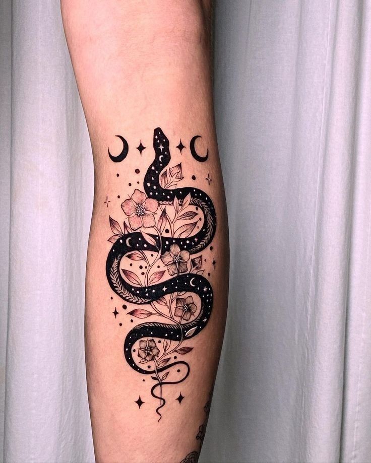 a woman's leg with a snake and flowers tattoo design on the left calf