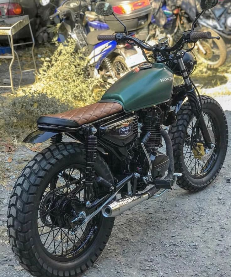 a green motorcycle parked on top of a dirt field