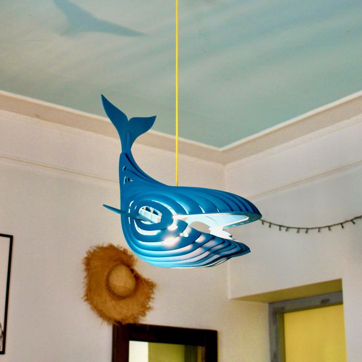 a blue whale mobile hanging from a ceiling in a room with white walls and lights