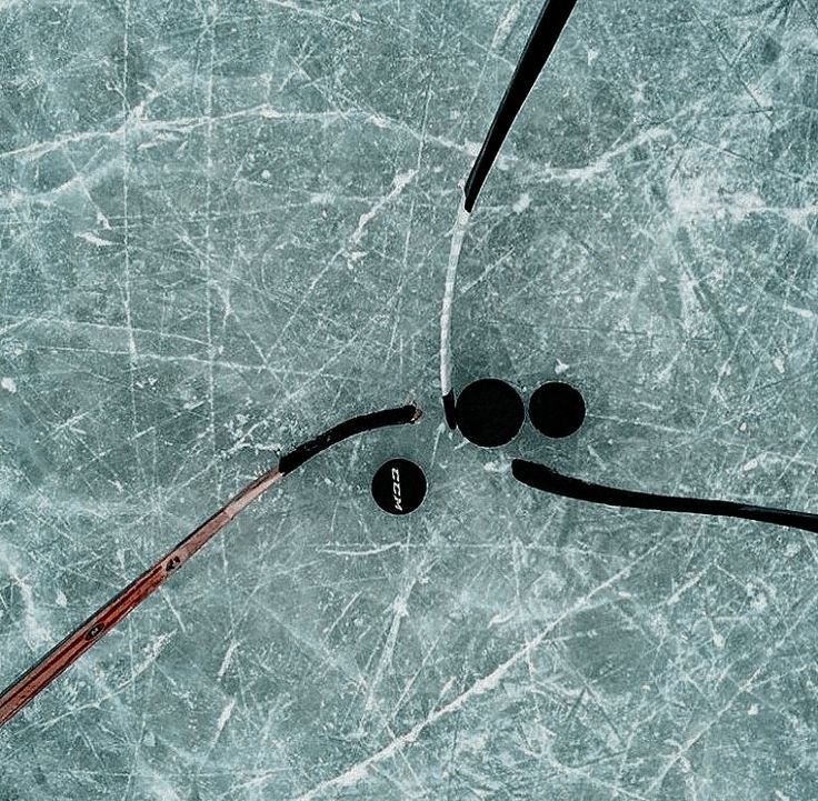 hockey sticks and puck laying on an ice rink