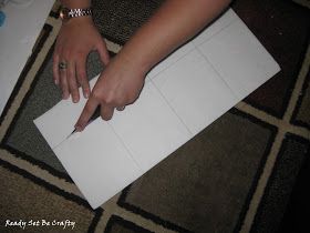 a person cutting paper with a knife on top of the floor next to a piece of paper