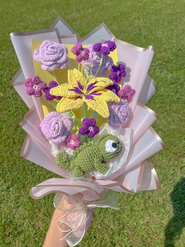 a person holding a bouquet of flowers in their hand with a frog on the side