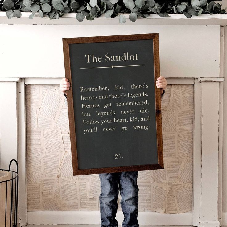 a young boy holding up a sign that says the sandlot on it's front