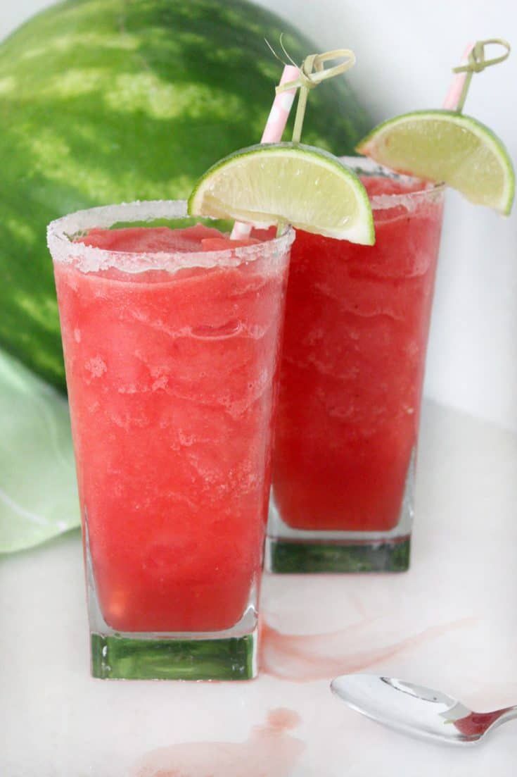 two glasses filled with watermelon slush and lime wedges