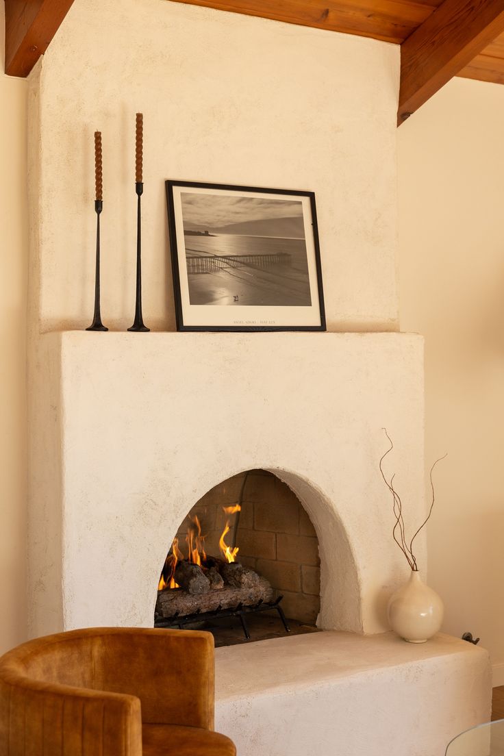 a fire place in a living room next to a chair and table with vases on it