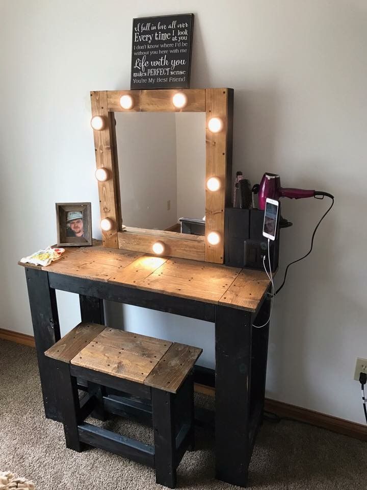 a wooden vanity with lights on it and a stool next to it in a room