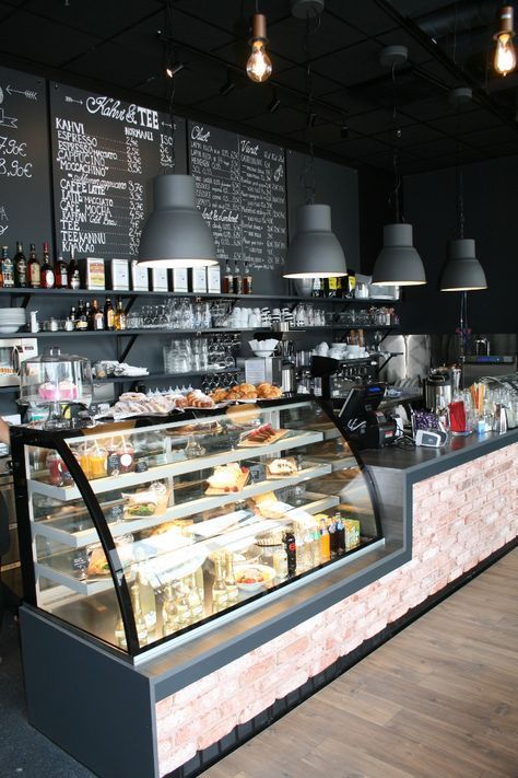 the inside of a deli with lots of food on display and lights hanging from the ceiling