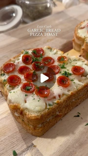 two slices of bread with tomatoes and cheese on them sitting on a wooden cutting board