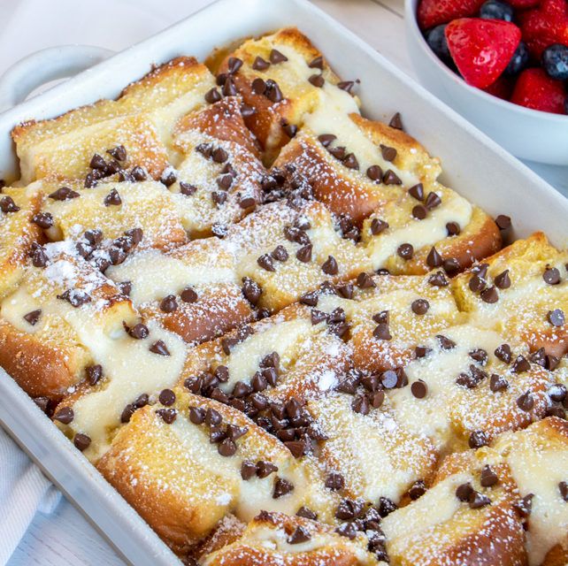 a pan filled with chocolate chip bread and topped with powdered sugar next to strawberries