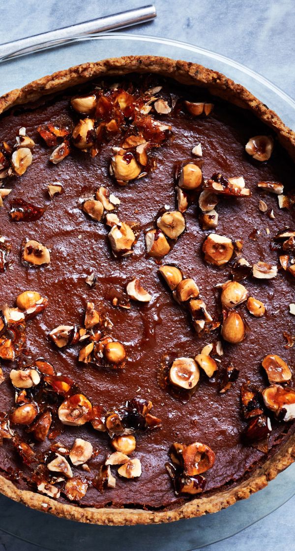 a chocolate pie topped with nuts on top of a table