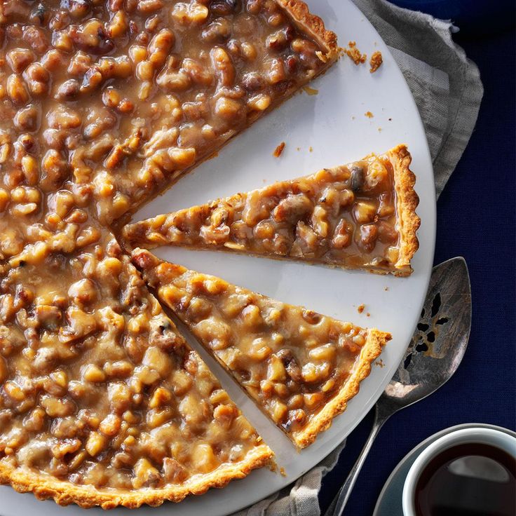 there is a pie that has been cut and served on a plate next to a cup of coffee