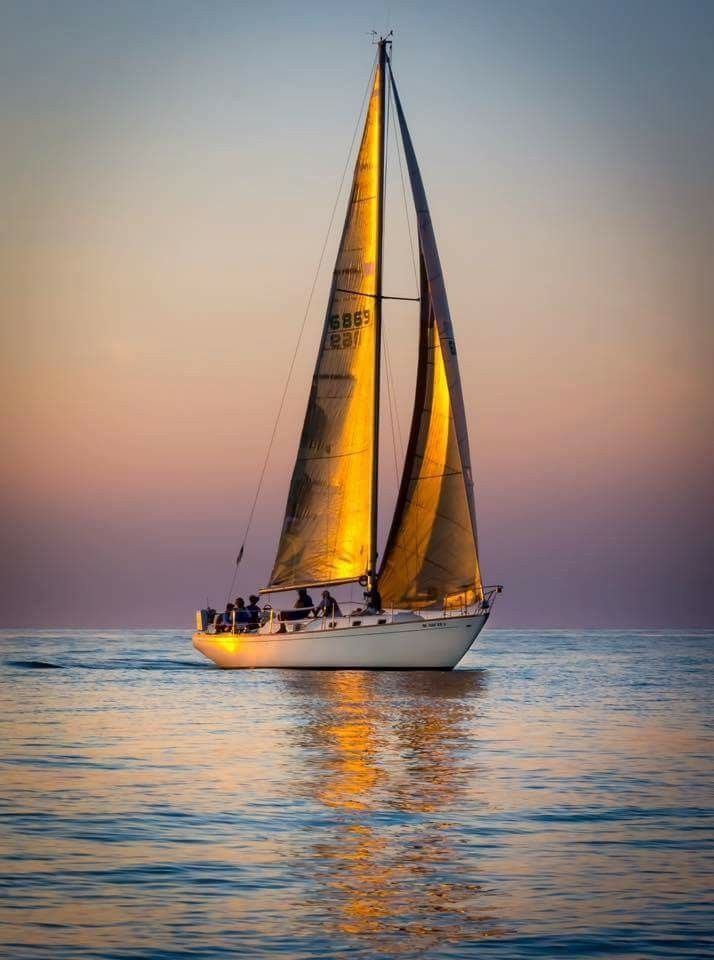 a sailboat sailing on the ocean at sunset