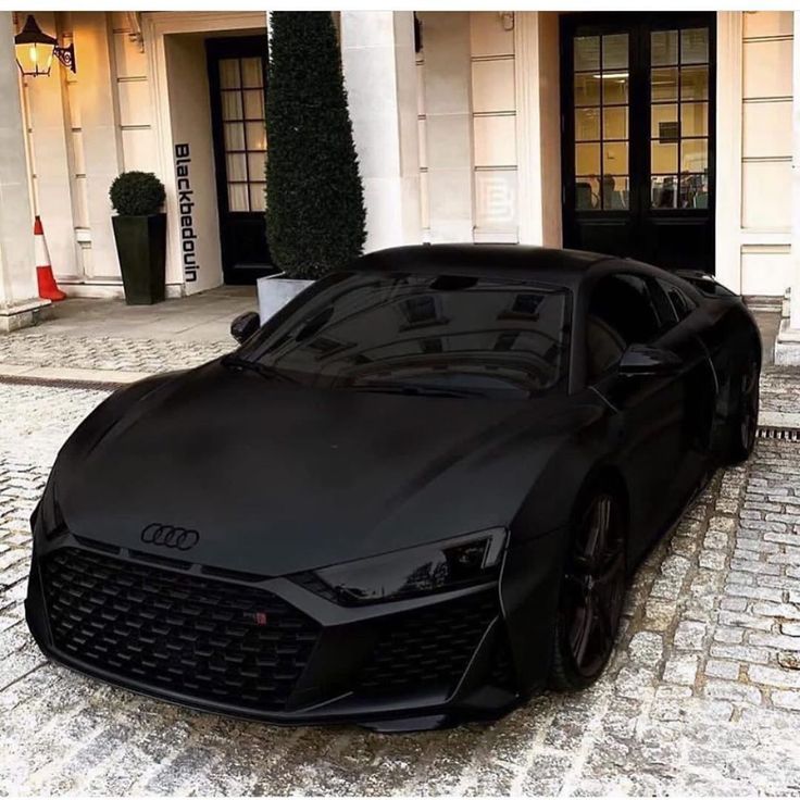 a black sports car parked in front of a building on a cobblestone street