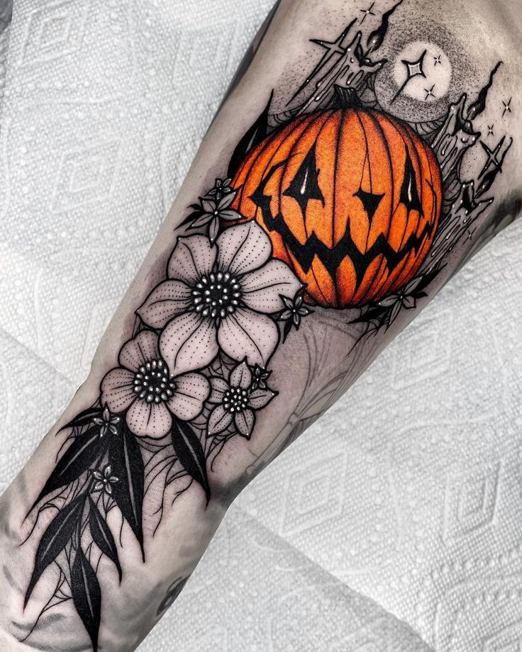 a tattoo with flowers and a pumpkin on the side of his arm, which is decorated with black dots