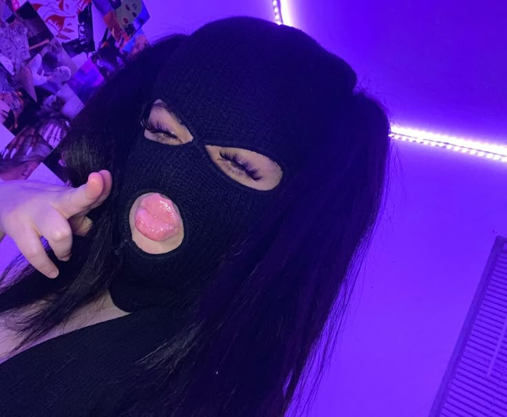 a woman wearing a black mask and pointing at the camera