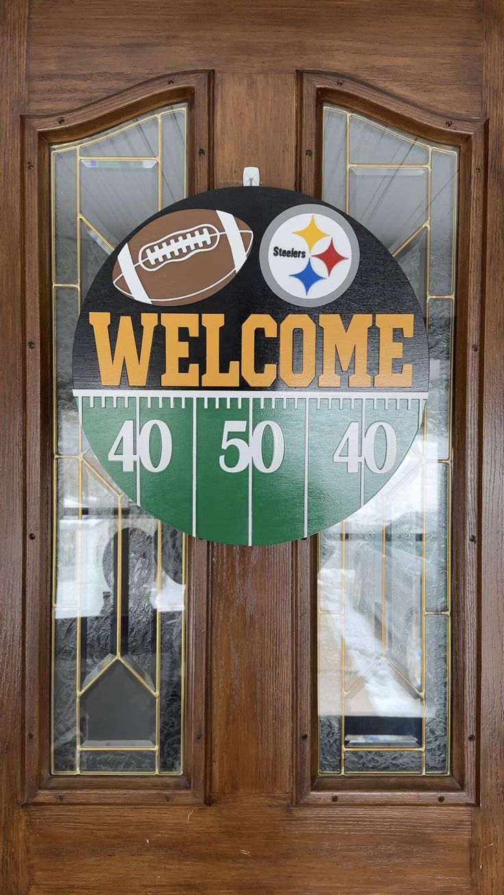 a wooden door with a welcome sign and footballs on the glass front paneling