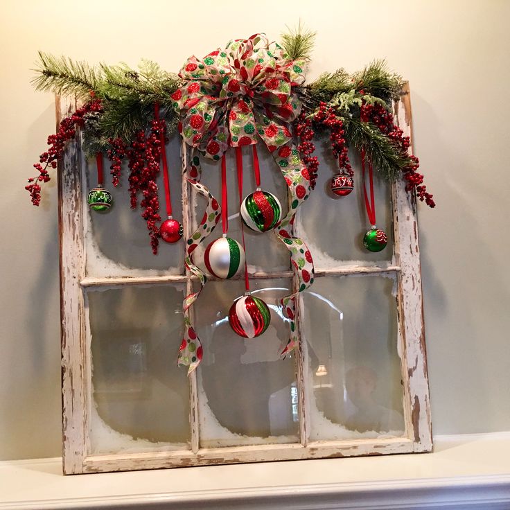 an old window decorated for christmas with ornaments and greenery hanging on the windowsill