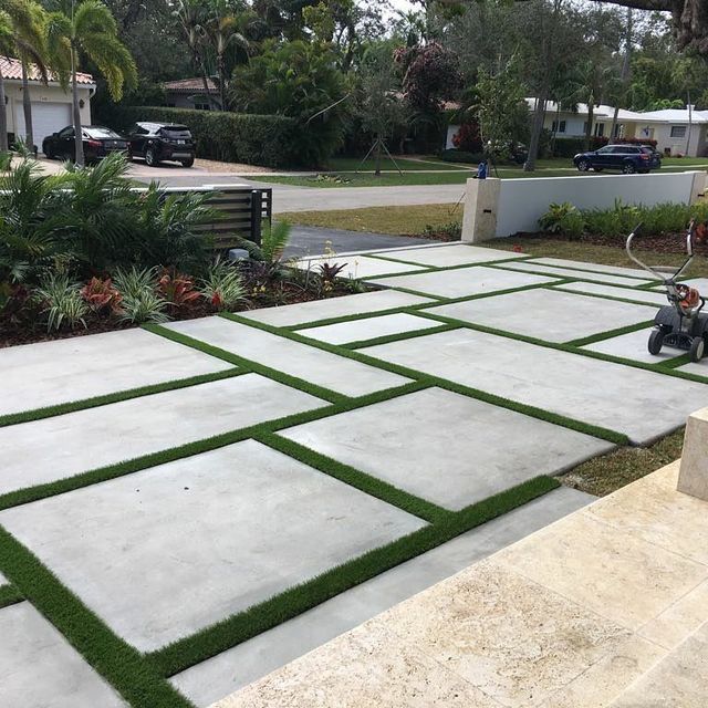 a man sitting on top of a cement bench in front of a lush green yard